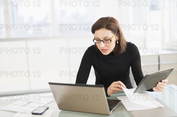 Businesswoman working on laptop and digital tablet.