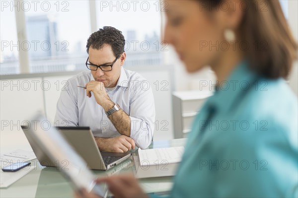 Businessman and businesswoman working in office.