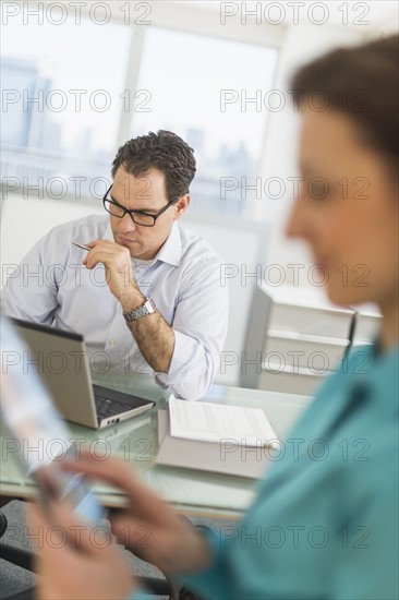 Businessman and businesswoman working in office.