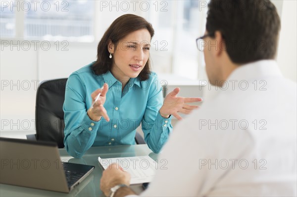 Businessman and businesswoman discussing in office.