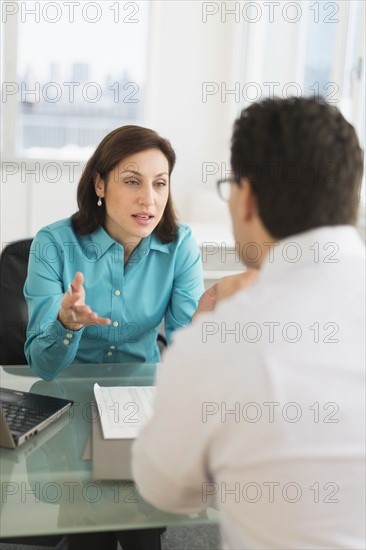 Businessman and businesswoman discussing in office.