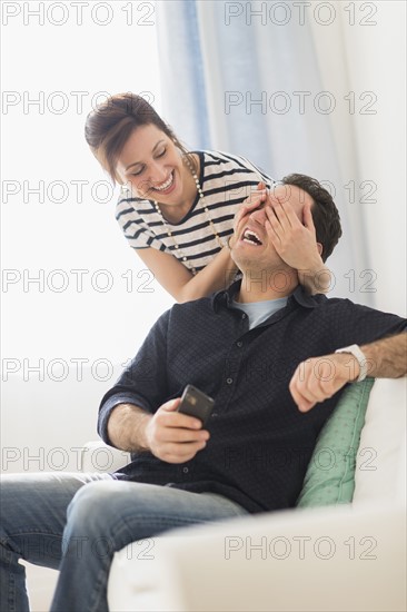 Woman covering man's eyes.