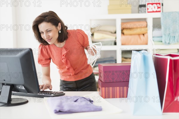 Woman using computer in clothes store.