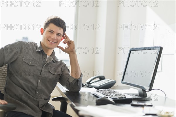 Young man sitting in front of desk.