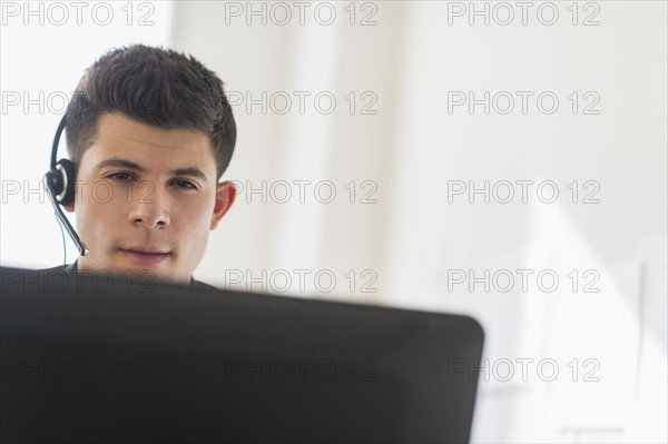Young man sitting in front of desk and talking.