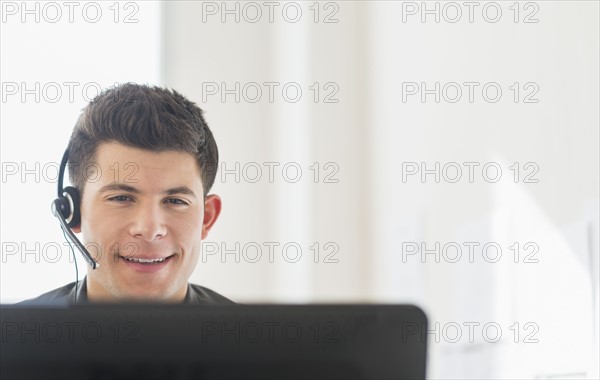 Young man sitting in front of desk and talking.