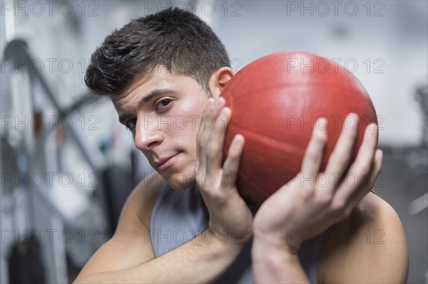 Young man at gym holding medicine ball.