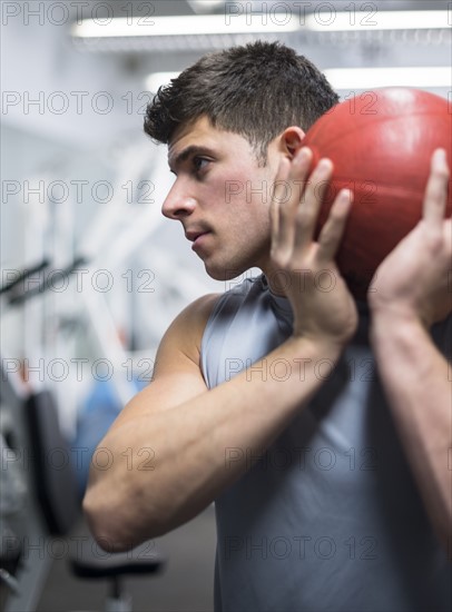 Young man at gym holding medicine ball.