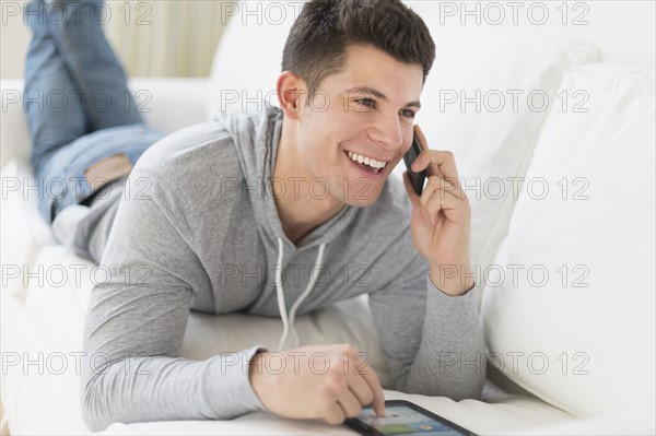 Young man using tablet and talking by phone.