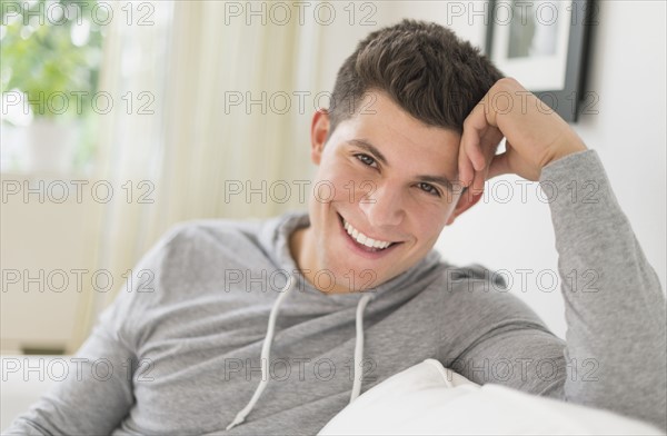 Young man sitting on sofa and smiling.