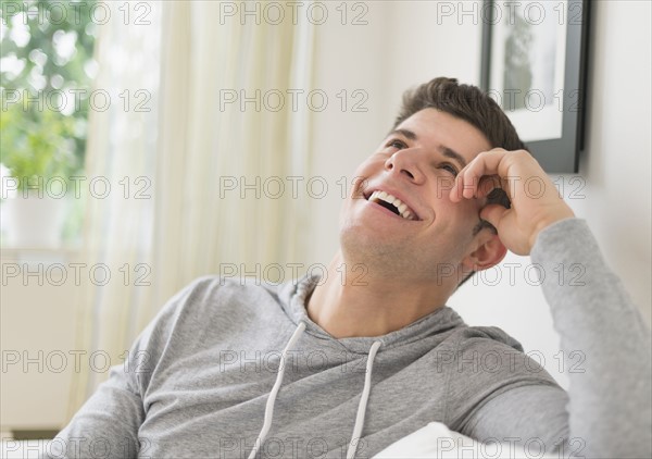 Young man sitting on sofa and smiling.