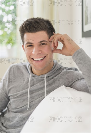 Young man sitting on sofa and smiling.