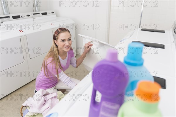 Woman loading laundry into washing machine.