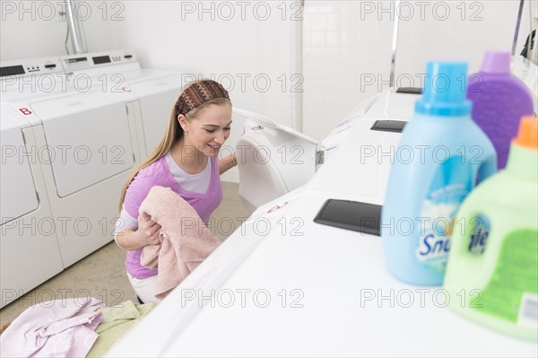 Woman loading laundry into washing machine.