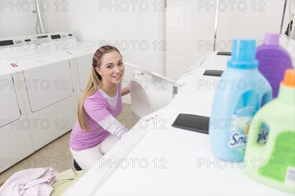 Woman loading laundry into washing machine.