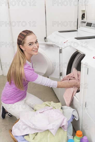 Woman loading laundry into washing machine.