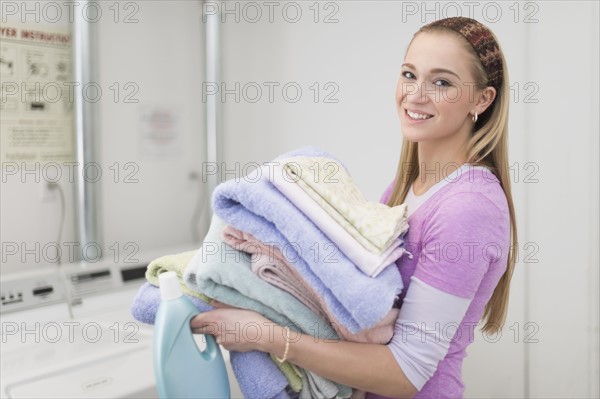 Woman carrying stack of clean towels.
