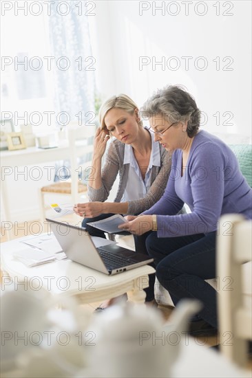 Two mature women paying bills via internet.