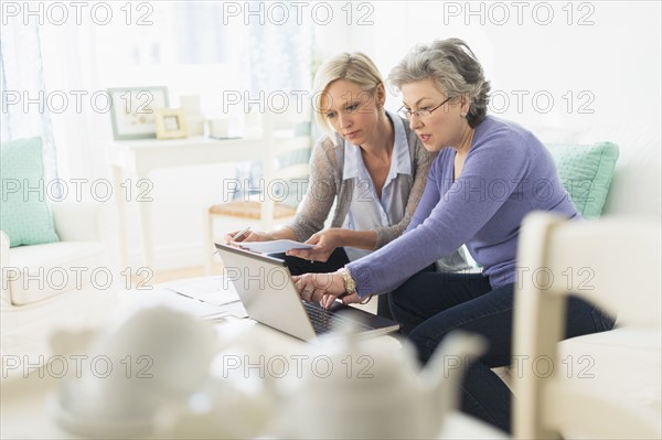 Two mature women paying bills via internet.