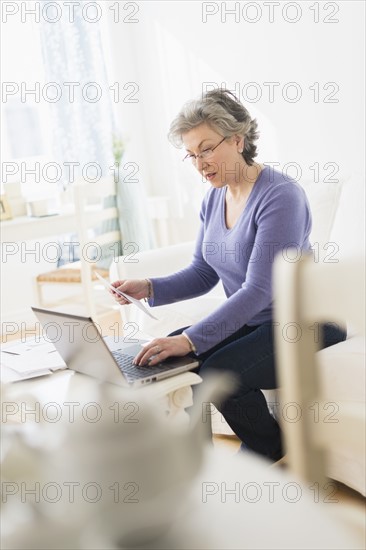 Mature woman paying bills via internet.