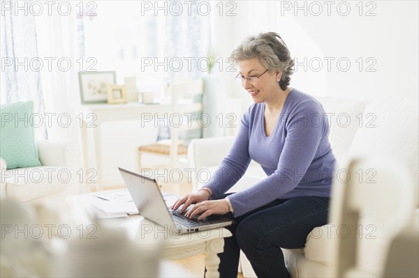 Mature woman paying bills via internet.