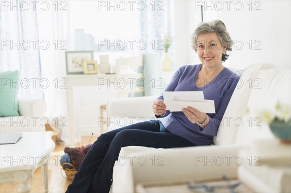 Woman sitting on coach reading letters.