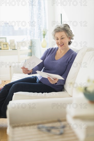 Woman sitting on coach reading letters.