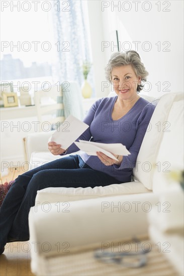 Woman sitting on coach reading letters.