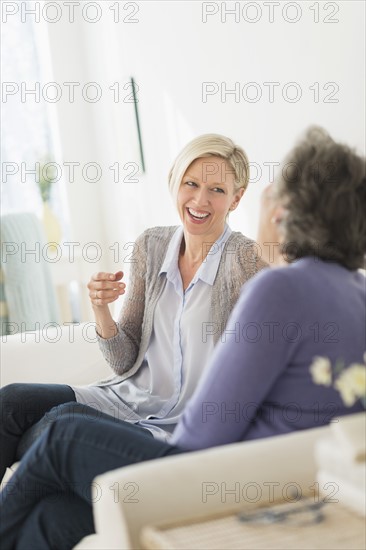 Two women sitting on coach talking.