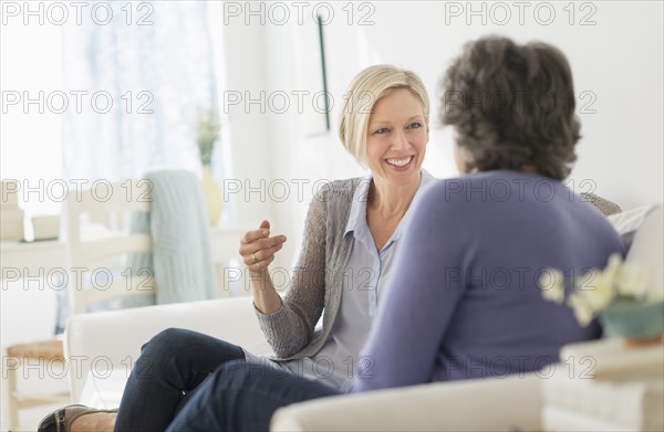 Two women sitting on coach talking.