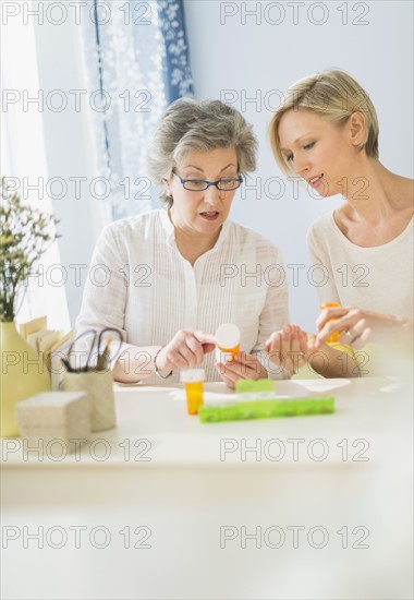 Nurse and mature woman reading labels on medicine bottle.