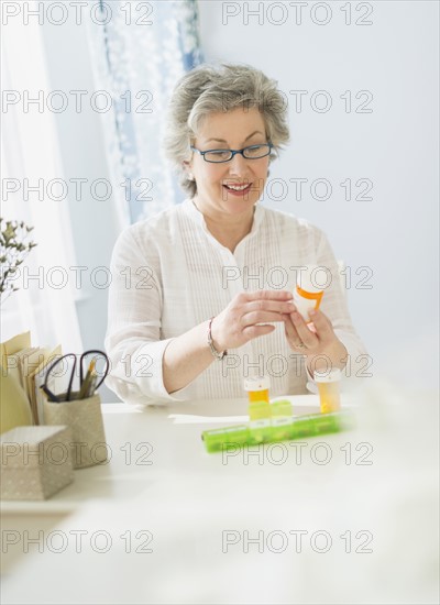 Mature woman reading labels on medicine bottle.