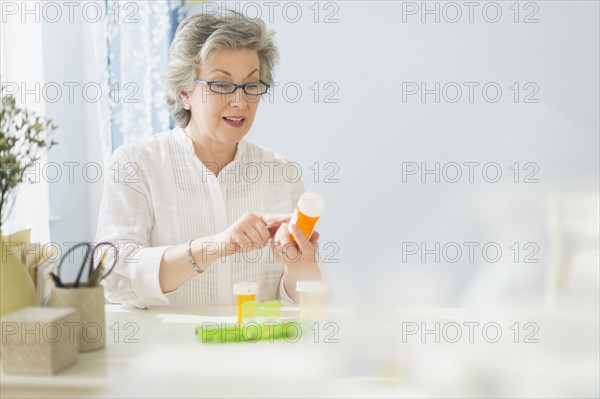 Mature woman reading labels on medicine bottle.