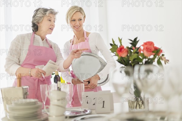 Two mature women preparing catering.