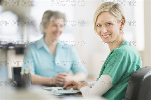 Portrait of female doctor, patient in background.