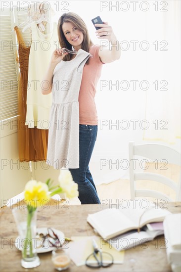 Woman trying on dress and taking self portrait.