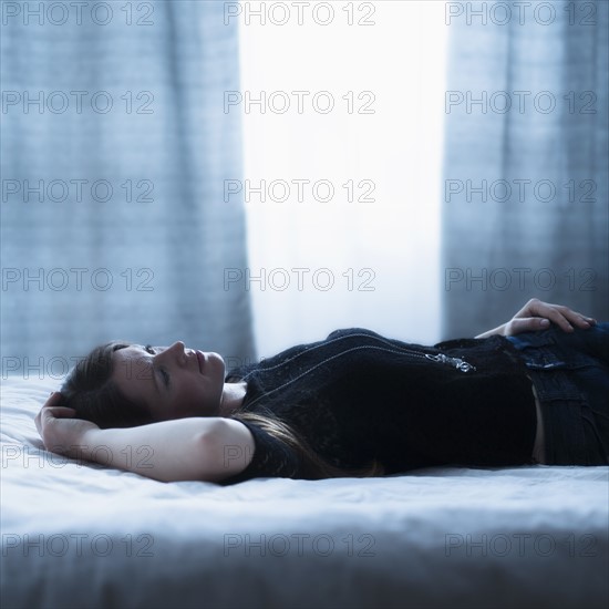 Portrait of beautiful woman lying down on bed.