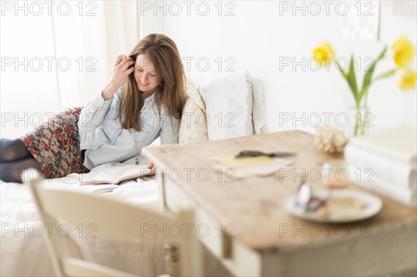 Woman lying on bed and writing diary.