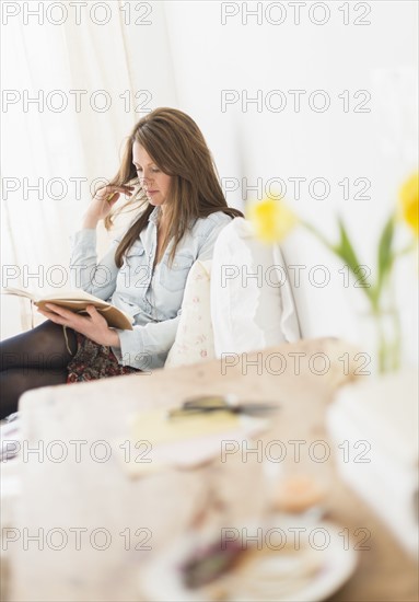 Woman sitting on bed and reading diary.