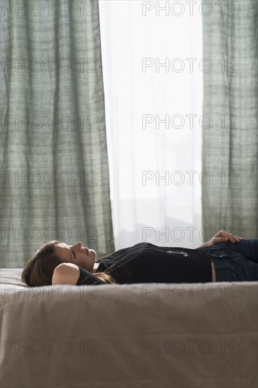 Portrait of beautiful woman lying down on bed.