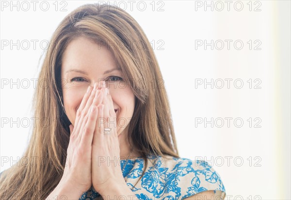 Portrait of woman laughing, hands on face.