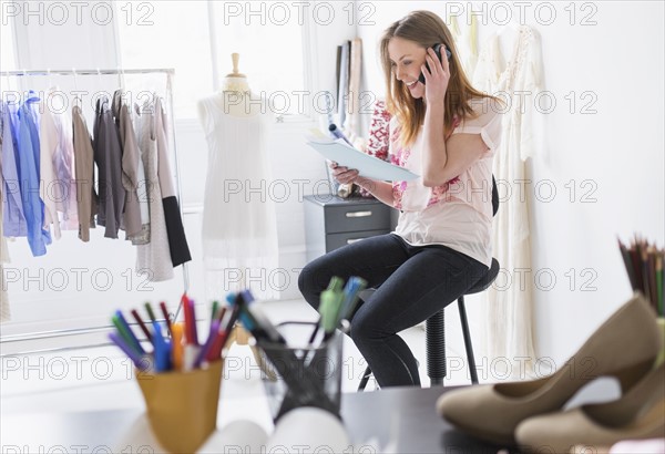 Portrait of female costume designer using mobile phone in studio.