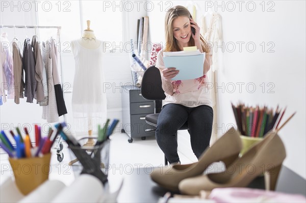 Portrait of female costume designer using mobile phone in studio.