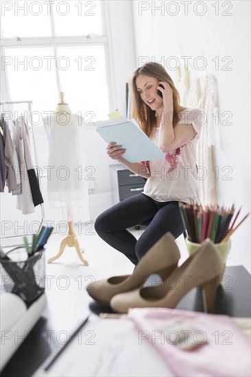 Portrait of female costume designer using mobile phone in studio.