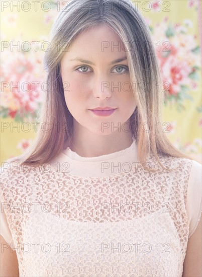 Portrait of young woman in front of floral wall paper.