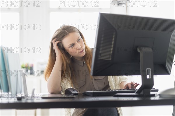 Portrait of young woman working on computer in office.