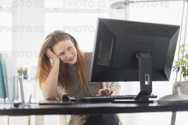 Portrait of young woman working on computer in office.