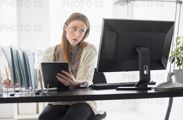 Portrait of young woman working digital tablet in office.