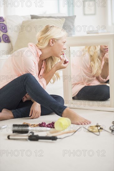 Young woman applying lipstick.
Photo : Jamie Grill