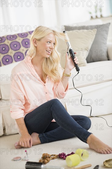 Young woman using curling tongs.
Photo : Jamie Grill